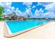 A community pool with crystal blue water and various seating areas under a partly cloudy sky at 489 Meadowood Blvd, Fern Park, FL 32730