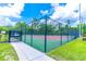A tennis court surrounded by a black chain link fence, nestled in a lush green lawn under a partly cloudy sky at 489 Meadowood Blvd, Fern Park, FL 32730