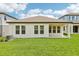 Backyard featuring a manicured lawn, a covered patio, and an exterior wall with multiple windows at 5308 Citrus Leaf Blvd, Winter Garden, FL 34787