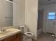 Standard bathroom featuring a sink, toilet, and shower-tub combo, adjacent to a door at 6610 Pampus Dr, Orlando, FL 32819