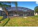 A large, fenced backyard features a screened patio with exterior kitchen at 826 Sheen Cir Cir, Haines City, FL 33844