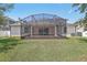 A backyard view of the screened-in patio overlooking a well-maintained lawn, ideal for outdoor activities at 827 Timber Isle Dr, Orlando, FL 32828