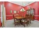 Formal dining room showcasing red accent walls and an elegant chandelier above a wooden table at 827 Timber Isle Dr, Orlando, FL 32828
