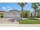 Charming two-story home showcasing a three-car garage, a lush green lawn, and beautiful tropical landscaping at 827 Timber Isle Dr, Orlando, FL 32828