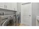 A functional laundry room features a modern washer and dryer set and upper cabinets for storage at 827 Timber Isle Dr, Orlando, FL 32828