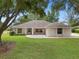 Charming single-story home featuring manicured lawn, mature trees, and neutral exterior paint at 11648 Grand Bay Blvd, Clermont, FL 34711