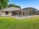 Back exterior view of a screened in pool with neutral paint and well maintained yard at 11648 Grand Bay Blvd, Clermont, FL 34711