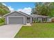 Charming single-story home features a well-manicured lawn, neutral gray paint, and a two-car garage at 122 Seville Rd, Auburndale, FL 33823