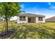 A well manicured backyard features lush lawn and a covered patio with brown trim at 1249 Champions Dr, Daytona Beach, FL 32124