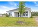 Beautiful backyard featuring a manicured lawn, freshly planted tree, and a covered patio perfect for relaxation at 1262 Champions Dr, Daytona Beach, FL 32124