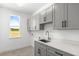 Bright laundry room with modern gray cabinetry, white countertops, and a window overlooking outdoors at 1262 Champions Dr, Daytona Beach, FL 32124