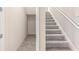 Carpeted stairway with white railings and an adjacent utility area featuring tiled floors at 1262 Champions Dr, Daytona Beach, FL 32124