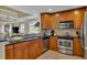 Well-lit kitchen with stainless appliances, wood cabinets, and tiled floors overlooks the dining area at 1354 Centre Court Ridge Dr # 104, Reunion, FL 34747