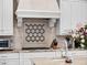 Close-up of the kitchen showcasing stone backsplash, professional cooktop, and custom hood at 1417 Terralago Pl, Oviedo, FL 32765