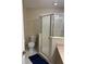 Neutral bathroom features a white toilet, shower with glass doors, and white tile floors at 1445 Valley Pine Cir, Apopka, FL 32712