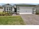 Charming one-story home featuring a brick-paved driveway and a two-car garage with stone veneer accents at 1580 Delphi Way, New Smyrna Beach, FL 32168