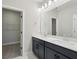 Bathroom vanity with double sinks, bright lighting, and a doorway leading to the walk-in closet at 16454 Silver Brook Way, Winter Garden, FL 34787