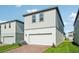Two-story home with light gray siding, a white garage door, and a brick driveway at 16454 Silver Brook Way, Winter Garden, FL 34787