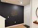 Modern entryway with wood-look floors, a dark accent wall with geometric art, and a bright white front door at 1900 Erudite Way, Winter Park, FL 32792