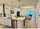 Modern kitchen with stainless steel appliances, white cabinets, quartz countertops, and pendant lighting overlooking the living room at 1900 Erudite Way, Winter Park, FL 32792