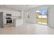 A bright kitchen with white cabinets, stainless steel appliances, tile floors, and sliding glass door at 2716 Pierr St, Davenport, FL 33837