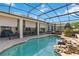 A lovely screened-in pool features a rock waterfall and stone surround, perfect for outdoor relaxation at 2746 Windsorgate Ln, Orlando, FL 32828