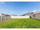 Large, grassy backyard is enclosed by a white fence, offering a safe and private outdoor space at 296 Inman Blvd, Winter Haven, FL 33881