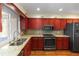 Modern kitchen with stainless steel appliances, granite countertops, and custom red wood cabinets at 3065 Bridgehampton Ln, Orlando, FL 32812