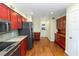 Traditional-style kitchen features red cabinetry, stainless steel appliances, granite countertops, and a beautiful hardwood floor at 3065 Bridgehampton Ln, Orlando, FL 32812