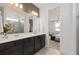 Bright bathroom with double vanity, large mirror, tiled shower, and open doorway to a bedroom with a comfortable seat at 3245 Ellsworth Ave, Davenport, FL 33837
