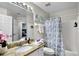 Well-lit bathroom offering a granite vanity, tub/shower combo with a floral shower curtain, and essential toiletries at 339 Holborn Loop, Davenport, FL 33897