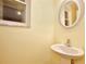 Charming powder room featuring a pedestal sink, decorative mirror, and a window for natural light at 4802 Anton Ave, Apopka, FL 32712