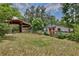 Exterior view of backyard area showcasing an outbuilding, a barn, green grass and a wooden fence at 4802 Anton Ave, Apopka, FL 32712
