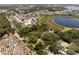 Aerial view of a red-roofed home surrounded by trees, near a pond and neighborhood at 5671 Cypress Gardens Rd, Winter Haven, FL 33884