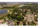 Aerial view of a red-roofed home among trees, alongside a pond, close to neighborhood homes and commercial buildings at 5671 Cypress Gardens Rd, Winter Haven, FL 33884