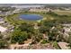 Aerial view of a red-roofed home surrounded by trees and a pond, with neighborhood and buildings nearby at 5671 Cypress Gardens Rd, Winter Haven, FL 33884