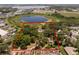 Aerial view of a red-roofed home located within a defined property line, surrounded by trees and near a pond at 5671 Cypress Gardens Rd, Winter Haven, FL 33884