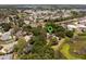 Aerial view of a red-roofed home with solar panels surrounded by trees in a residential area at 5671 Cypress Gardens Rd, Winter Haven, FL 33884