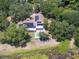 Aerial view of a red-roofed home with solar panels and a backyard pool surrounded by lush greenery and tall trees at 5671 Cypress Gardens Rd, Winter Haven, FL 33884