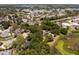 Aerial view of a red-roofed home surrounded by trees, near a pond, with neighborhood and buildings nearby at 5671 Cypress Gardens Rd, Winter Haven, FL 33884
