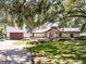 Charming home featuring a well-manicured lawn, mature trees, and a brick-accented facade at 5671 Cypress Gardens Rd, Winter Haven, FL 33884