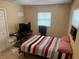 A cozy bedroom with a striped bedspread and a window providing natural light at 625 E Jackson Ave, Mount Dora, FL 32757
