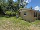 Exterior view of a yard with sparse grass, trees and partial view of home's exterior wall with window at 625 E Jackson Ave, Mount Dora, FL 32757