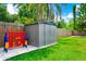 Backyard shed and connect-four game, surrounded by a lush lawn and wooden fence at 7616 Simms Ave, Orlando, FL 32812