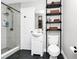 Bathroom with tiled shower, modern vanity, and black shelving unit for storage and organization at 7616 Simms Ave, Orlando, FL 32812