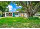 Charming single-story home featuring a modern design, a well-manicured lawn, and a large shade tree at 7616 Simms Ave, Orlando, FL 32812
