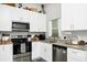 Well-lit kitchen featuring white cabinets, modern stainless steel appliances and granite countertops at 7616 Simms Ave, Orlando, FL 32812