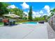 Backyard pool with patio umbrella, seating, mature trees, privacy fence, and lawn at 7616 Simms Ave, Orlando, FL 32812