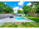 Backyard pool with patio seating, surrounded by mature trees, lush landscaping, and privacy fence at 7616 Simms Ave, Orlando, FL 32812