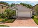Exterior view of a single-story home showcasing a two-car garage and a brick paved driveway at 879 Nonastone Run, Casselberry, FL 32707